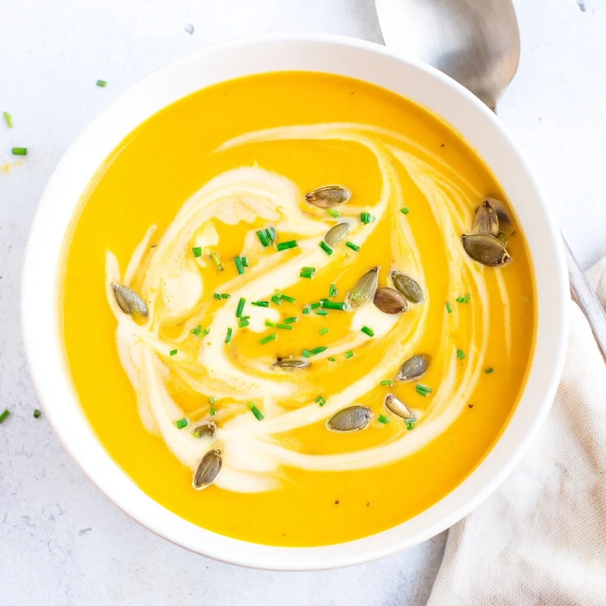 Steaming bowl of velvety butternut squash soup sprinkled with pumpkin seeds and parsley for comfort food dinner