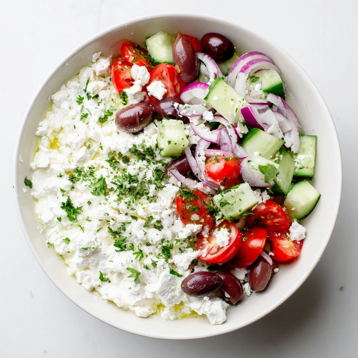 Creamy cottage cheese bowl layered with crisp vegetables, olives, and crumbled feta cheese