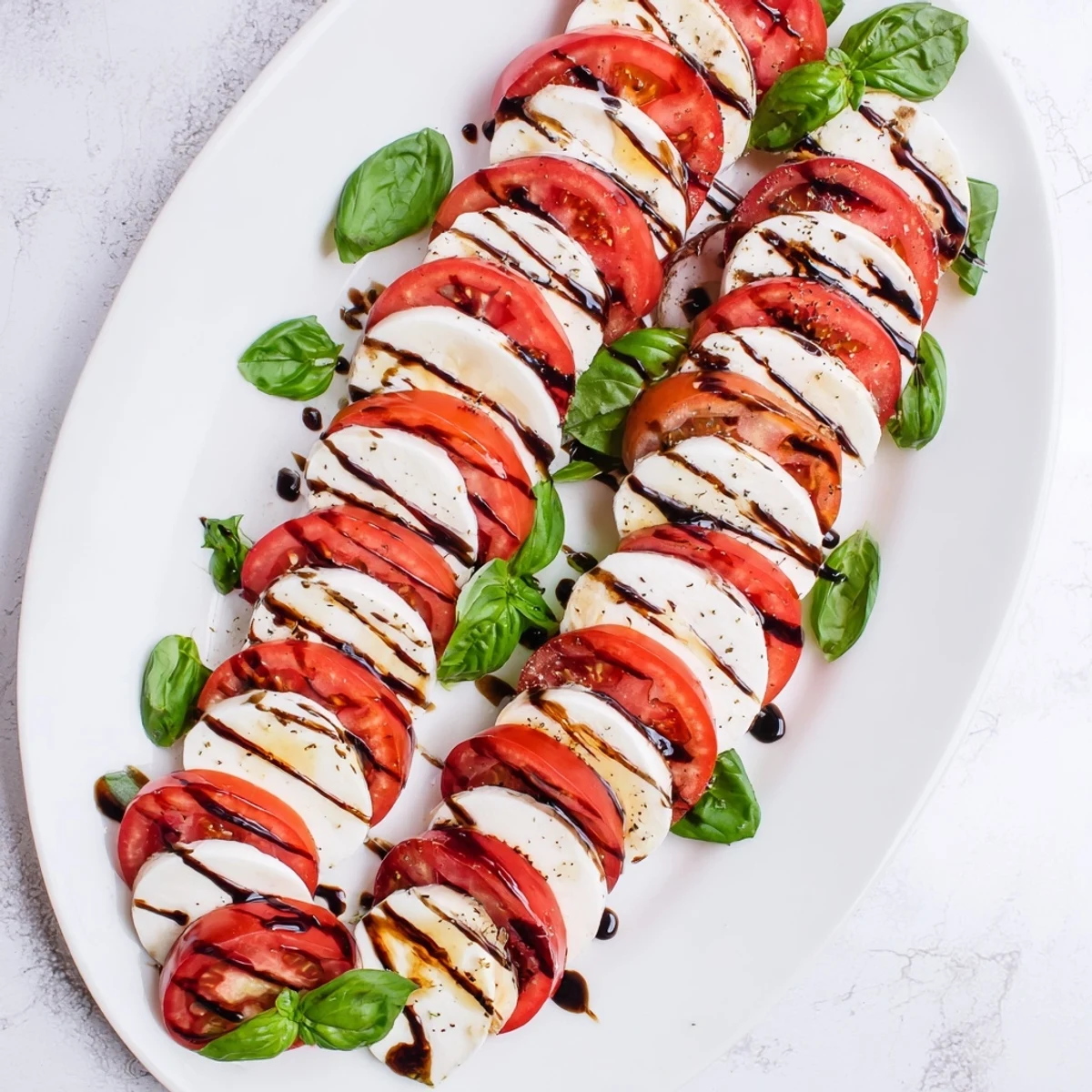 Festive Christmas candy cane Caprese salad arranged with ripe tomato slices and fresh mozzarella on a white serving platter