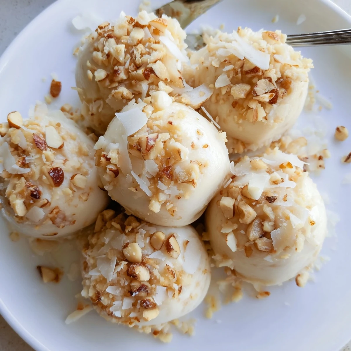 Frozen Banana Yogurt Bites arranged on parchment, creamy white coating, sprinkled coconut