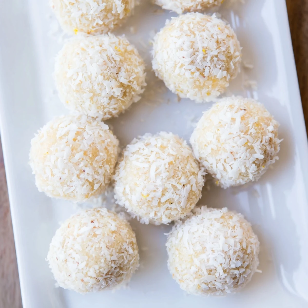 Fresh no-bake Citrus Bliss Bites topped with lemon zest on a wooden board