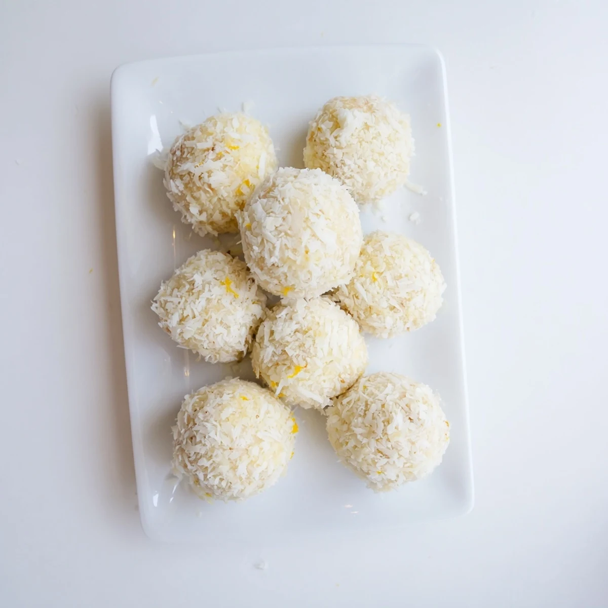 Golden Citrus Bliss Bites rolled in coconut, arranged on a white serving platter