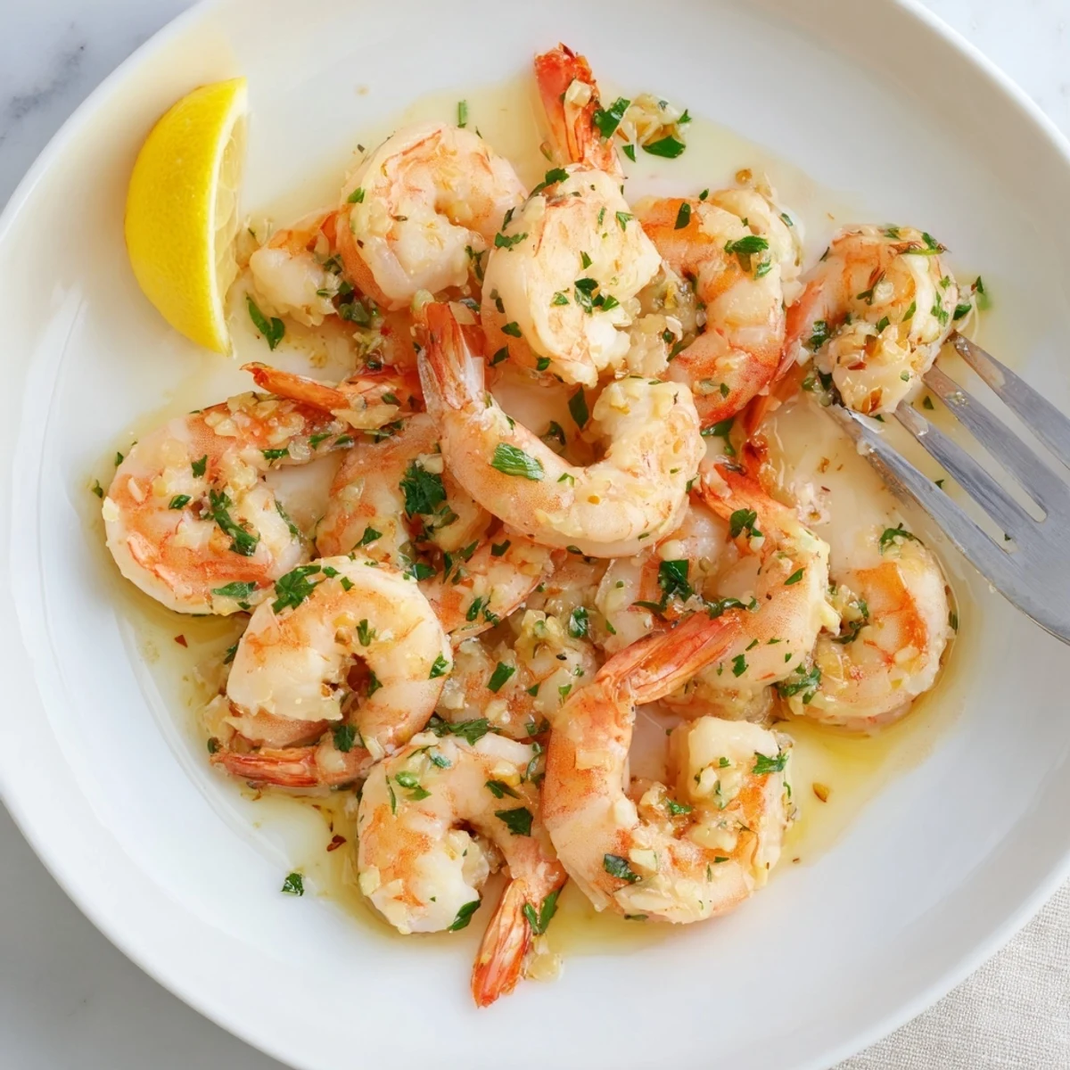 Sizzling skillet of buttered shrimp tossed with minced garlic and bright lemon wedges