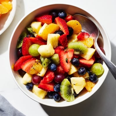 Fresh fruit bowl arranged on a white platter with vibrant seasonal berries